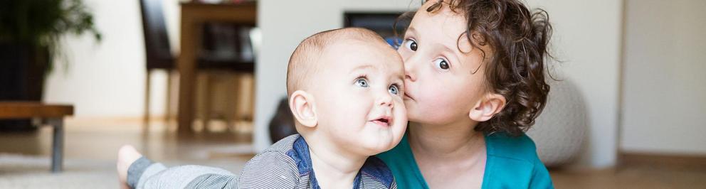 Boy gives his baby brother a kiss