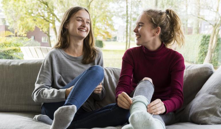 twee lachende jonge dames op de bank