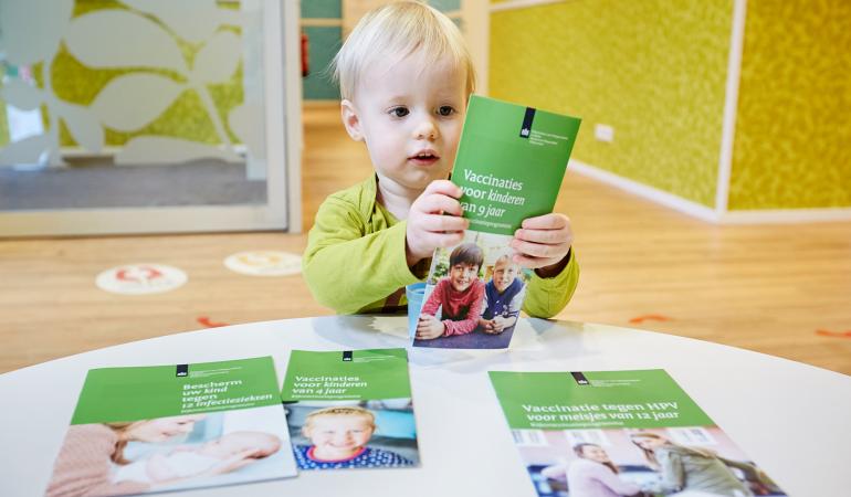 Jongetje bekijkt leaflets van het Rijksvaccinatieprogramma