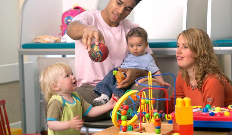 Vader en moeder met jonge kinderen aan het spelen met speelgoed