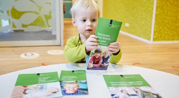 jongetje bekijkt de folders van het Rijksvaccinatieprogramma