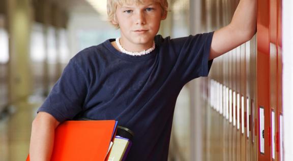 tiener jongen met ordner onder zijn arm bij schoolkluisje
