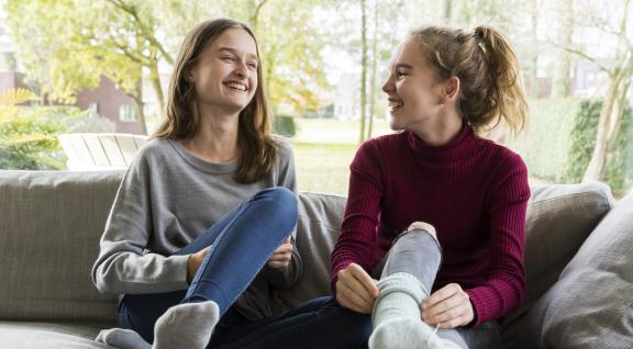 twee lachende jonge dames op de bank