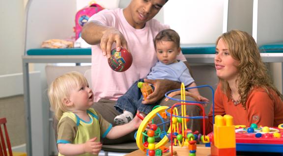 Vader en moeder met jonge kinderen aan het spelen met speelgoed
